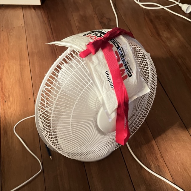 Tying a gel pack to the top of a fan with a red ribbon